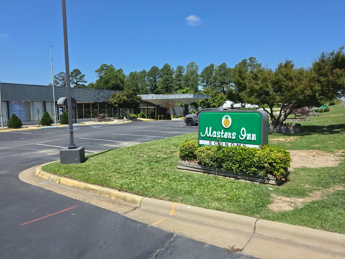 Entrada cubierta, estacionamiento y letrero de Masters Economy Inn en Selma, Carolina del Norte