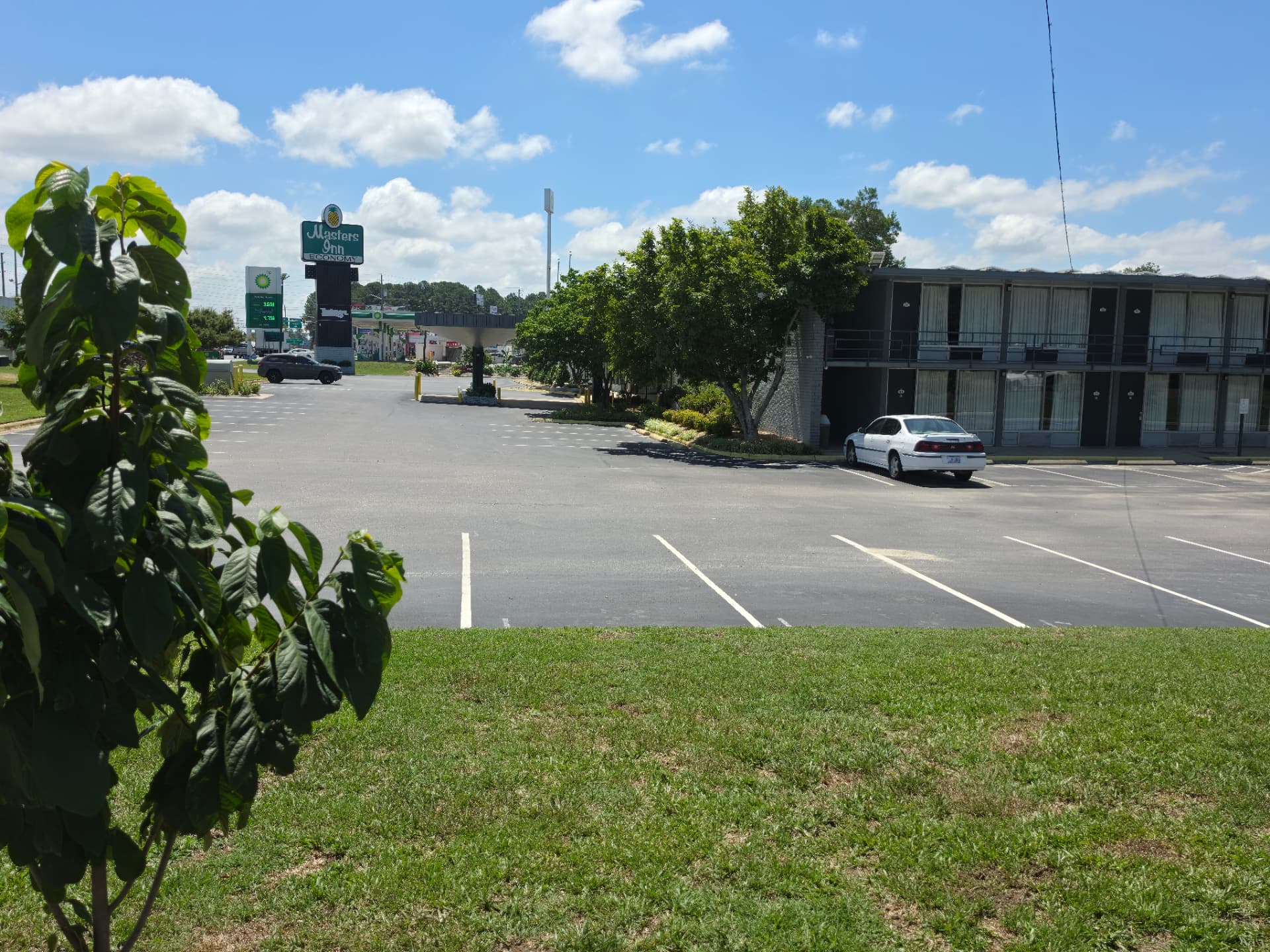 The Masters Economy Inn pineapple sign and parking lot with the guest room building alongside US Highway 70 East