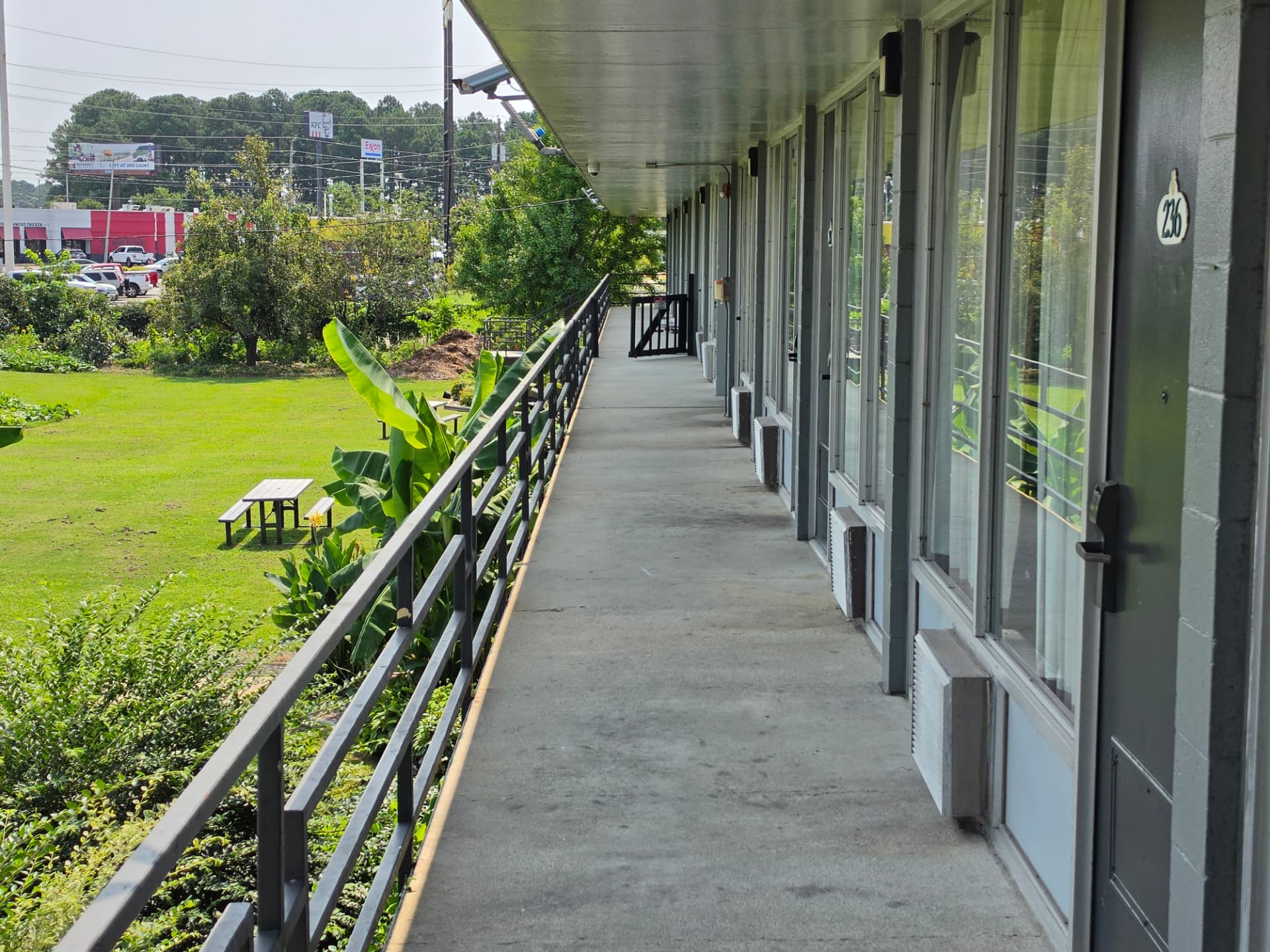 An upper-floor exterior walkway at Masters Economy Inn overlooking the lawn and picnic table