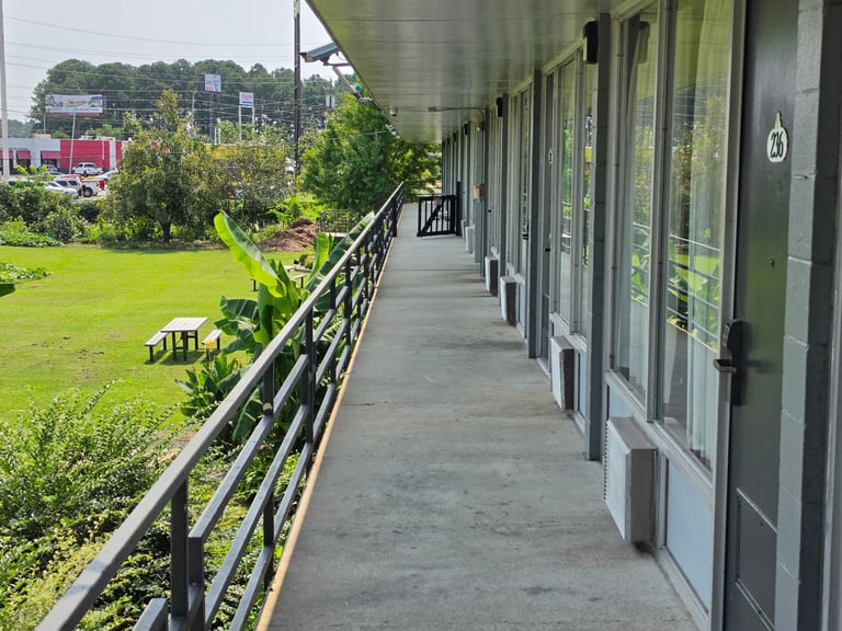 An upper-floor exterior walkway at Masters Economy Inn overlooking the lawn and picnic table