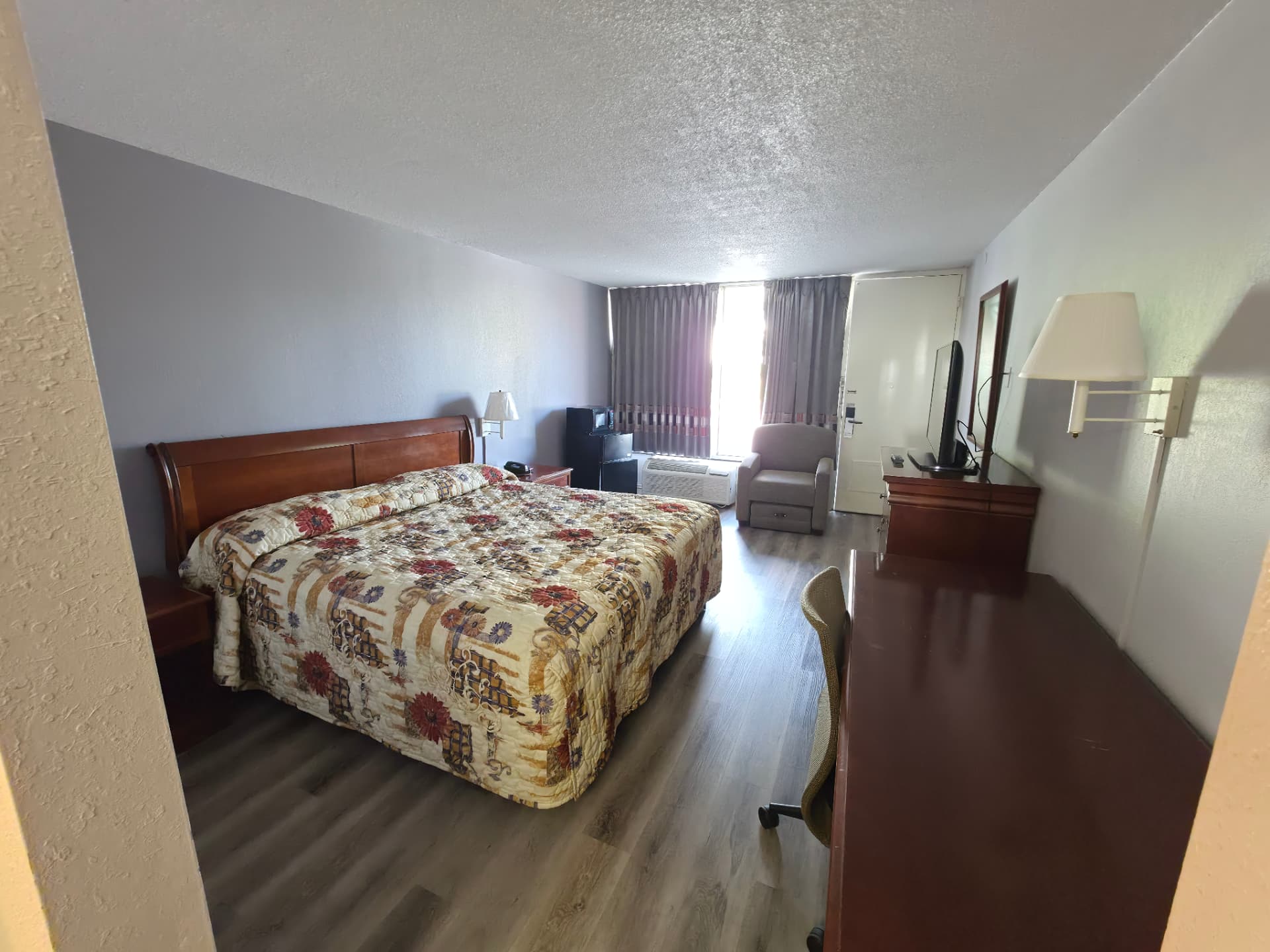King room at Masters Economy Inn with a king bed, armchair, desk and flat-screen TV