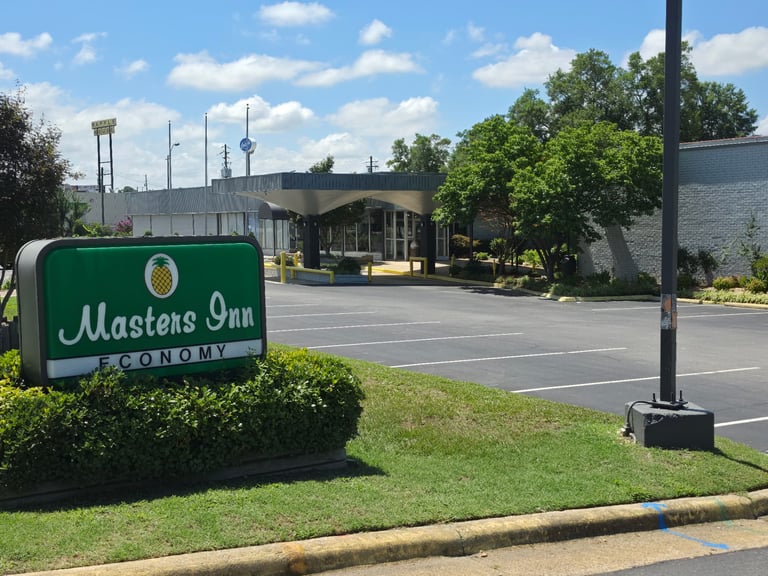 The green Masters Economy Inn pineapple road sign in front of the property on US Highway 70 East