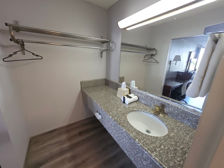 King room dressing area with hanging rail, granite vanity, mirror and towels